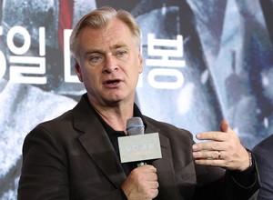 Christopher Nolan gestures while speaking into a microphone at a press conference for 'The Odyssey' in Korea.