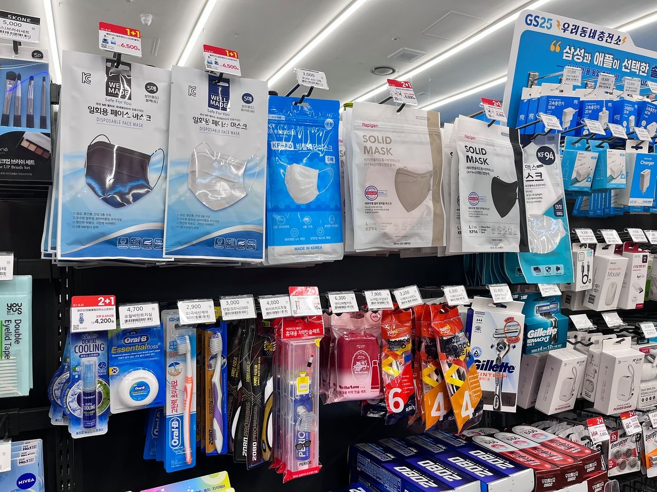 Various face masks displayed for sale on shelves at a GS25 convenience store, alongside toothbrushes, razors and other personal care items.