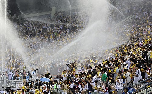 Baseball fans in the stands are sprayed with mist from water cannons to cool off during a game at a stadium in Seoul.